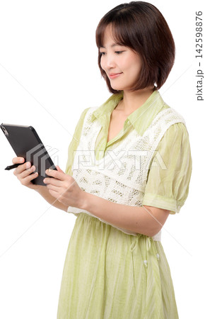 Asian woman using tablet in light green dress with gentle smile isolated on transparent background 142598876