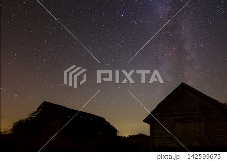 Starry sky over wooden houses in the village. Starry sky background picture of stars in night sky and the Milky Way. 142599673