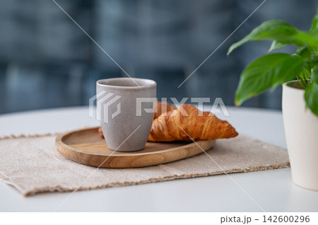 Coffee and Croissant on a Minimalist Table with Green Plant 142600296