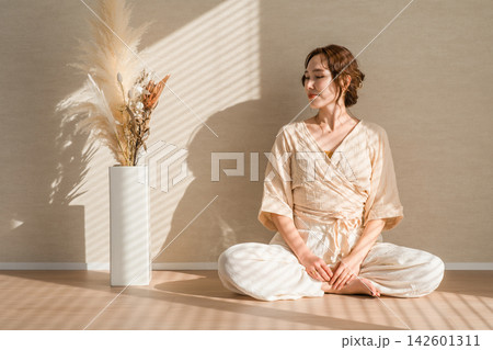 柔らかな日差しの中で穏やかな自分時間を過ごす女性。心を整えるウェルビーイングな暮らし 柔らかな日差しの中で穏やかな自分時間を過ごす女性。心を整えるウェルビーイングな暮らし 142601311