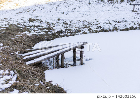 Wooden pier on a frozen lake with snow cover 142602156