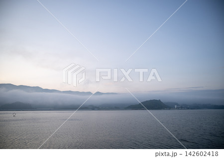 初夏の早朝4時半の静寂な海と山裾を低く覆う幻想的な朝靄の風景 初夏の早朝4時半の静寂な海と山裾を低く覆う幻想的な朝靄の風景 142602418