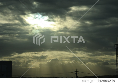 空と黒い雲の隙間から見える薄明光線の降り注ぐ風景 空と黒い雲の隙間から見える薄明光線の降り注ぐ風景 142603219