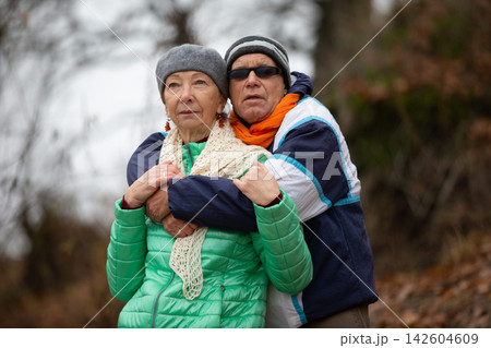 Couple enjoys outdoor moment together on a chilly day in the woods with trees in the background 142604609