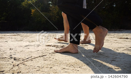 Male and female legs of pair walking on sandy beach. Bare feet of couple stepping along sand shore at sunny day. Lovers spending time together at resort. Concept of summer vacation or holiday Male and female legs of pair walking on sandy beach. Bare feet of couple stepping along sand shore at sunny day. Lovers spending time together at resort. Concept of summer vacation or holiday 142604790