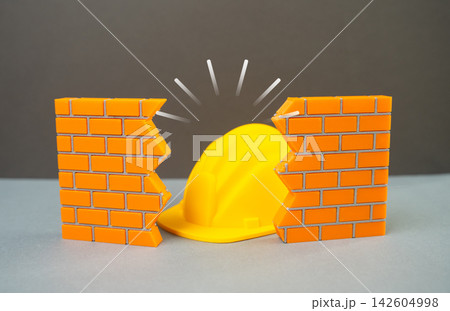 Construction helmet visible through a hole in the wall, repair and reconstruction, building and infrastructure fixing concept. Renovation work, structural maintenance, property restoration Construction helmet visible through a hole in the wall, repair and reconstruction, building and infrastructure fixing concept. Renovation work, structural maintenance, property restoration 142604998