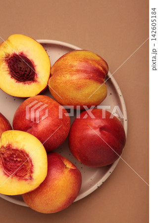 Fresh ripe nectarine on plate on brown background. Vertical photo Fresh ripe nectarine on plate on brown background. Vertical photo 142605184