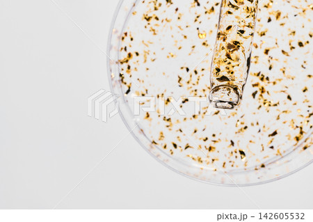 Golden skincare serum with gold flakes in glass dropper and petri dish on white background Golden skincare serum with gold flakes in glass dropper and petri dish on white background 142605532