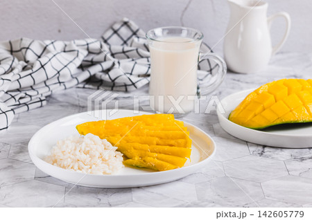 Making a trendy dessert of mango, rice, and coconut milk on a plate on the table Making a trendy dessert of mango, rice, and coconut milk on a plate on the table 142605779