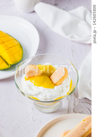 Mango trifle with savoiardi in a bowl on the table vertical view 142605800