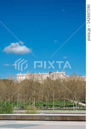 Royal Palace of Madrid rising above spring park trees under a blue sky with the moon Royal Palace of Madrid rising above spring park trees under a blue sky with the moon 142607290