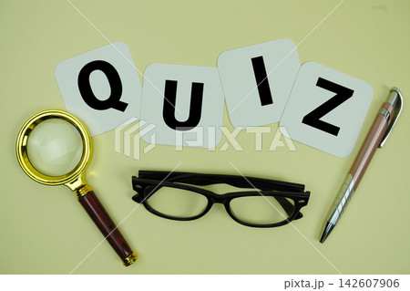 QUIZ alphabet letters with magnifying glass, eye glasses and pen on yellow background 142607906