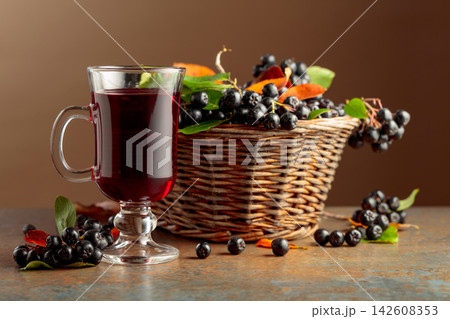 Glass of chokeberry drink and fresh berries. 142608353