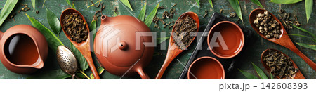 Assorted Loose Leaf Teas with Clay Teapot and Teacups on Rustic Surface Assorted Loose Leaf Teas with Clay Teapot and Teacups on Rustic Surface 142608393