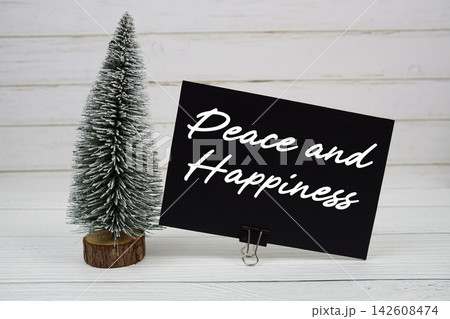 Peace and Happiness text written on paper card with snowy tree on wooden background Peace and Happiness text written on paper card with snowy tree on wooden background 142608474