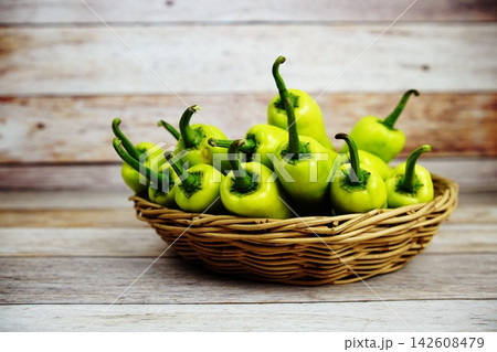 Fresh raw green bell pepper in bamboo basket on wooden background Fresh raw green bell pepper in bamboo basket on wooden background 142608479
