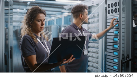 IT Specialists Collaborating on Laptop in Data Center Server Room 142608554