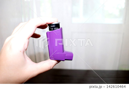 A woman holding an asthma inhaler with an expiration date A woman holding an asthma inhaler with an expiration date 142610464