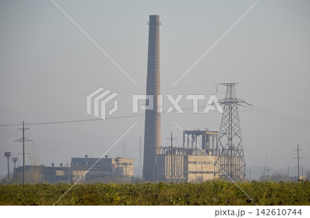 pipes and power plant building in the rays of the sun at sunset 142610744