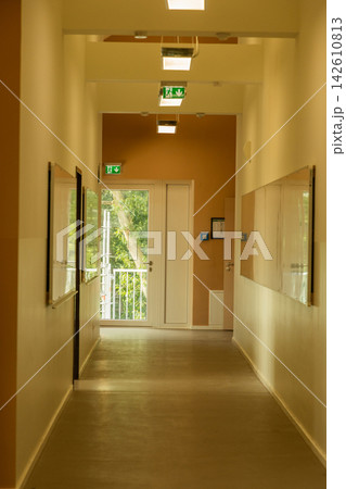 Bright corridor with modern lighting and large windows showcasing nature Bright corridor with modern lighting and large windows showcasing nature 142610813