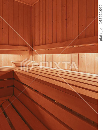 Wooden Sauna with Tiered Benches. Empty wooden sauna with tiered timber benches, soft warm illumination. Modern wellness interior suitable for spa, relaxation, recovery, thermal treatment Wooden Sauna with Tiered Benches. Empty wooden sauna with tiered timber benches, soft warm illumination. Modern wellness interior suitable for spa, relaxation, recovery, thermal treatment 142611069