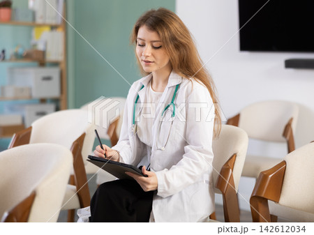 During lecture, young woman medical listener makes notes on tablet During lecture, young woman medical listener makes notes on tablet 142612034