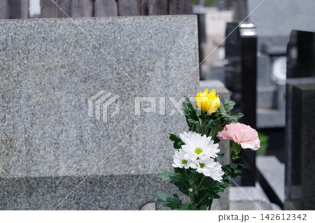 墓石にお供えされた菊やカーネーションの色鮮やかな仏花 142612342