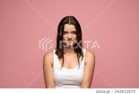Young woman showing disgust, frowning her face, feeling grumpy and annoyed on a pink background Young woman showing disgust, frowning her face, feeling grumpy and annoyed on a pink background 142612675