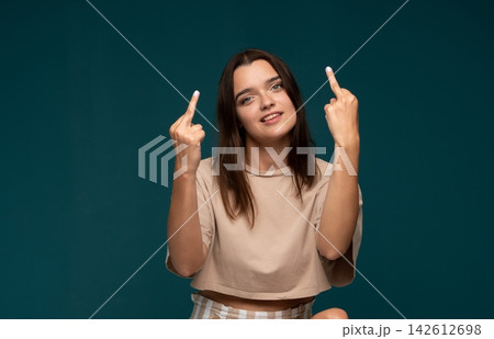 Young woman confidently showing middle fingers to camera, expressing defiance and strong attitude Young woman confidently showing middle fingers to camera, expressing defiance and strong attitude 142612698