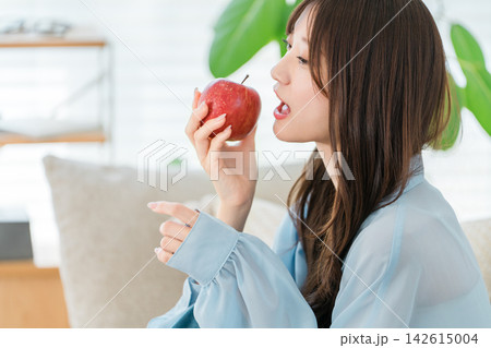 健康と美容を意識して赤いりんごを食べようとする若い女性のヘルシーな食生活 142615004