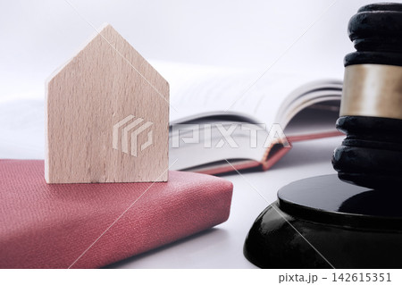 Wooden house, judge gavel and books with white background on table. Asset forfeiture, foreclosure and real-estate law concept Wooden house, judge gavel and books with white background on table. Asset forfeiture, foreclosure and real-estate law concept 142615351