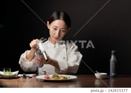 ガスバーナーで食材に火を入れる女性シェフ ガスバーナーで食材に火を入れる女性シェフ 142615377