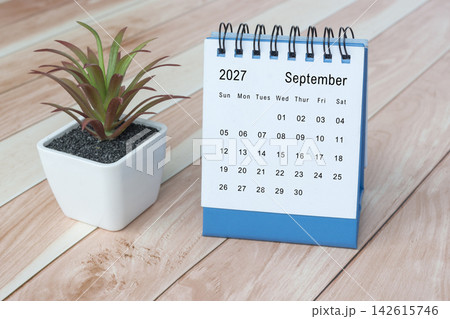September 2027 desk calendar with potted plant on wooden desk. September 2027 desk calendar with potted plant on wooden desk. 142615746