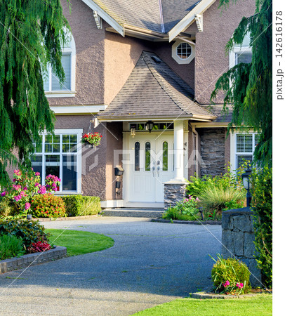 Main entrance of suburban home with paved driveway and landscaped garden 142616178