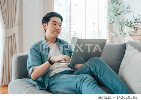 Young Asian man relaxing on comfortable couch 142619568