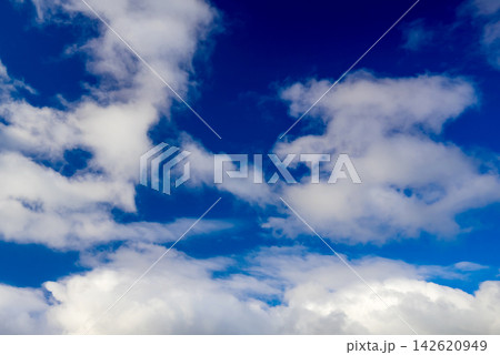 fluffy white clouds float across a bright blue sky on a sunny summer day fluffy white clouds float across a bright blue sky on a sunny summer day 142620949