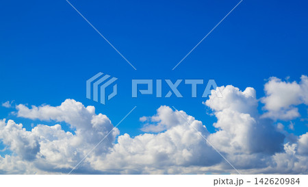 white fluffy clouds line the bottom of a wide clear blue sky white fluffy clouds line the bottom of a wide clear blue sky 142620984
