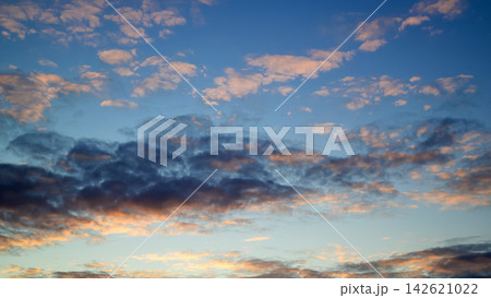 dramatic sunset sky filled with dark contrast clouds and gold illuminated ripple cloudlets 142621022