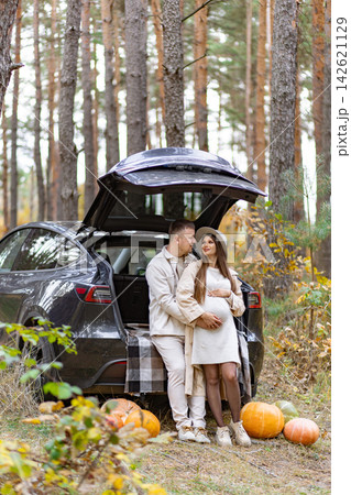A loving couple expecting a baby enjoys a beautiful autumn day in the woods, surrounded by pumpkins A loving couple expecting a baby enjoys a beautiful autumn day in the woods, surrounded by pumpkins 142621129