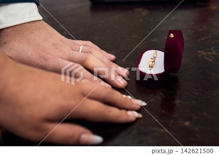 View of a couple's hands, placing their wedding rings on their fingers, in a civil ceremony; detail of their rings. Romance, bride and groom, union, love 142621500