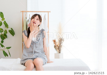 朝のベッドで眠そうにぼんやりする若い女性・寝起きや睡眠不足をイメージする朝時間 朝のベッドで眠そうにぼんやりする若い女性・寝起きや睡眠不足をイメージする朝時間 142621515