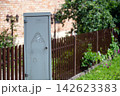 Electrical distribution cabinet in a garden near a wooden fence 142623383