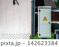 Cabinet stands in front of a house beside a road on a sunny day with trees in the background 142623384