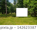 Large blank billboard stands in the park surrounded by trees and open grass 142623387