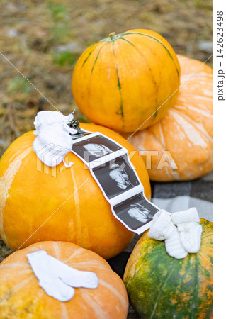 A creative pregnancy announcement features pumpkins, baby booties, and an ultrasound scan 142623498