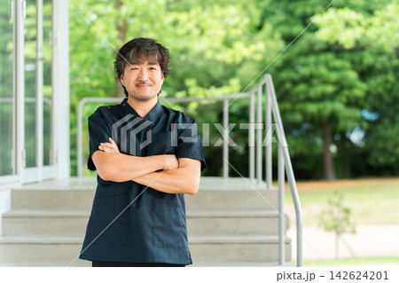 腕を組んで笑顔を見せるスクラブ姿の男性医師・外科医や専門医 腕を組んで笑顔を見せるスクラブ姿の男性医師・外科医や専門医 142624201