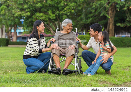 cheerful family taking care of elderly grandmother in wheelchair outdoors at park 142624962