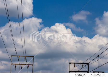 立体的な白雲と青空の広がりを背景に架線柱と電線(き電線)が走る風景 - 見上げるアングル 立体的な白雲と青空の広がりを背景に架線柱と電線(き電線)が走る風景 - 見上げるアングル 142625190