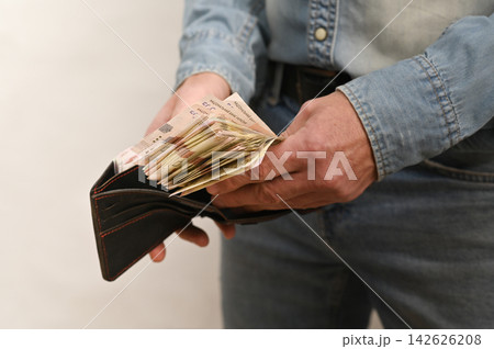 Hand holds open wallet overflowing with crisp banknotes. Hand holds open wallet overflowing with crisp banknotes. 142626208