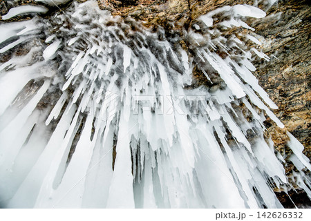 Ice icicles hanging on stone surface of cave, frozen water lake Baikal in winter 142626332